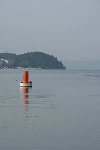 Makedonya 'nın Ohri Gölü' nde gün doğumu. Suda kırmızı bir şamandıra ve arka planda dağlar olan güzel bir manzara..