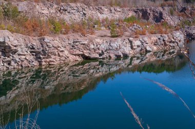 Taş ocağında kayalık bir kıyısı ve berrak suyu olan bir göl manzarası..