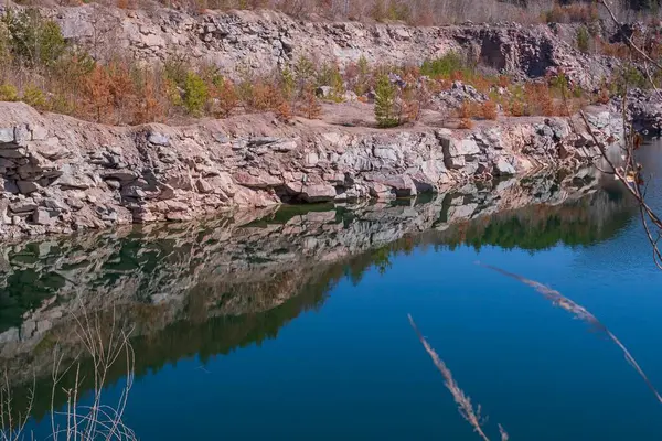 Taş ocağında kayalık bir kıyısı ve berrak suyu olan bir göl manzarası..