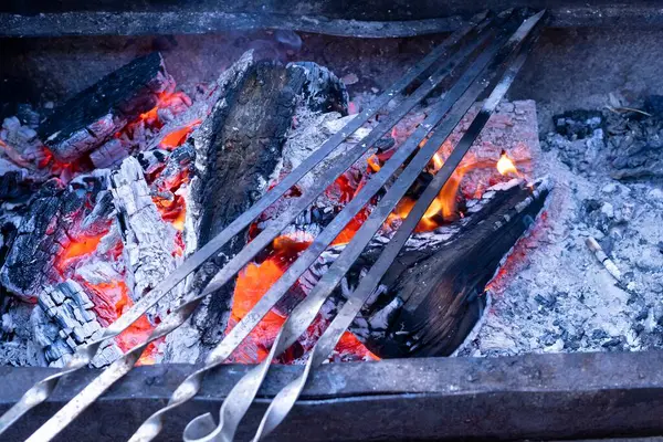 Açık havada yemek pişirmek için Kamp Ateşinde Metal Şiş Yanan Kömür