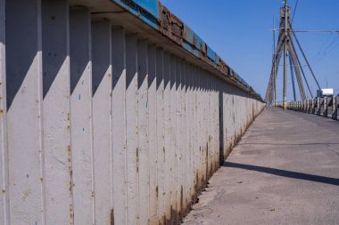 İlkbaharda yoğun bir yol boyunca nehrin üzerindeki köprünün kaldırımında. Modern mimari. Şehrin köprüsü.