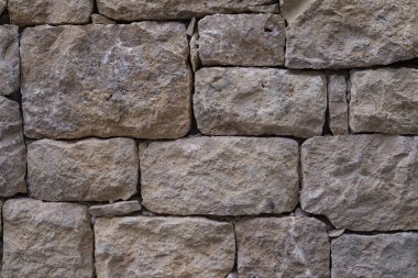 Düz olmayan taş bloklardan yapılmış eski taş duvar. İşlenmiş kaba taşın dokusu.