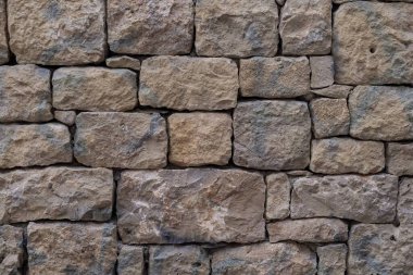 Düz olmayan taş bloklardan yapılmış eski taş duvar. İşlenmiş kaba taşın dokusu.
