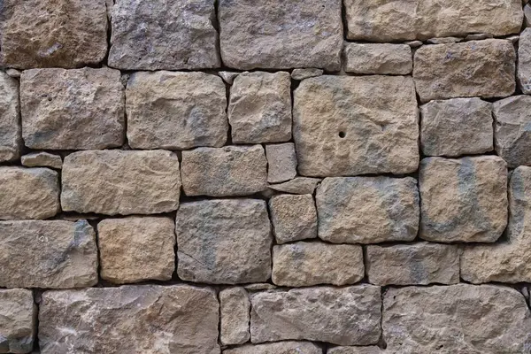 Düz olmayan taş bloklardan yapılmış eski taş duvar. İşlenmiş kaba taşın dokusu.
