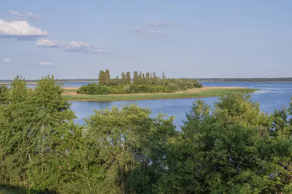 Geniş bir nehir ve kıyı boyunca yoğun bitki örtüsüyle güzel bir manzara..