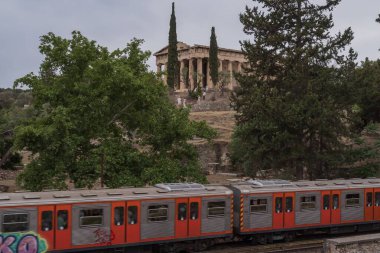 Yunanistan 'ın Monastyraki bölgesindeki Atina' daki antik Akropolis kentinden bir metro treni geçiyor. Atina, 23 Mayıs 2025