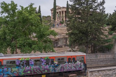 Yunanistan 'ın Monastyraki bölgesindeki Atina' daki antik Akropolis kentinden bir metro treni geçiyor. Atina, 23 Mayıs 2025