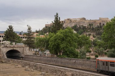 Yunanistan 'ın Monastyraki bölgesindeki Atina' daki antik Akropolis kentinden bir metro treni geçiyor. Atina, 23 Mayıs 2025
