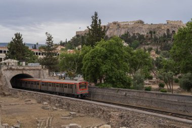Yunanistan 'ın Monastyraki bölgesindeki Atina' daki antik Akropolis kentinden bir metro treni geçiyor. Atina, 23 Mayıs 2025