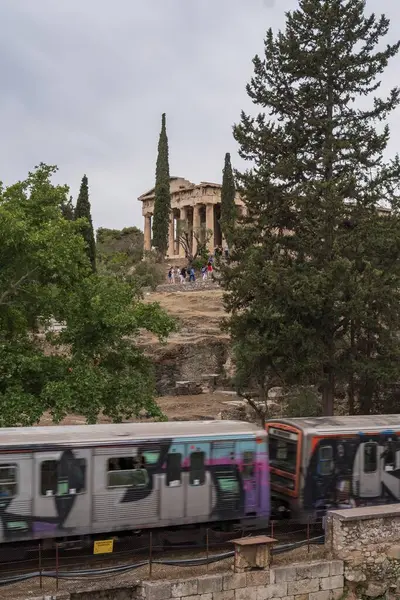 Yunanistan 'ın Monastyraki bölgesindeki Atina' daki antik Akropolis kentinden bir metro treni geçiyor. Atina, 23 Mayıs 2025