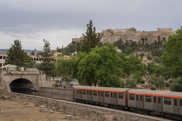 Yunanistan 'ın Monastyraki bölgesindeki Atina' daki antik Akropolis kentinden bir metro treni geçiyor. Atina, 23 Mayıs 2025