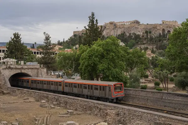 Yunanistan 'ın Monastyraki bölgesindeki Atina' daki antik Akropolis kentinden bir metro treni geçiyor. Atina, 23 Mayıs 2025