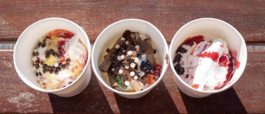 Dolapta donmuş Yunan yoğurdu ve güneş ışığı altında ahşap bankta malzemeler var.