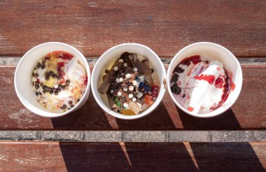 Dolapta donmuş Yunan yoğurdu ve güneş ışığı altında ahşap bankta malzemeler var.