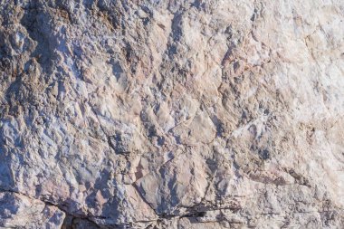 Doğal pembe ve gri damarlı yıpranmış taşın yakın çekimi. Taş dokusu, tasarım için arkaplan