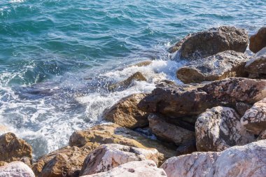 Deniz dalgaları kayalık kıyıya yuvarlanır ve büyük kayalara çarpar, köpük oluşturur..