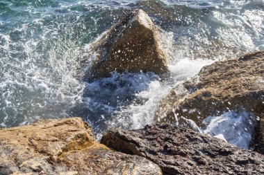 Atina gezinti güvertesinde gün batımının ışınlarında dalgalanan dalgalarla kayalık deniz kıyısı