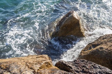 Atina gezinti güvertesinde gün batımının ışınlarında dalgalanan dalgalarla kayalık deniz kıyısı