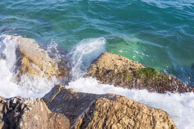 Atina gezinti güvertesinde gün batımının ışınlarında dalgalanan dalgalarla kayalık deniz kıyısı