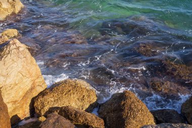 Atina gezinti güvertesinde gün batımının ışınlarında dalgalanan dalgalarla kayalık deniz kıyısı