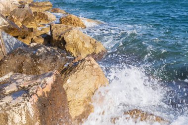Atina gezinti güvertesinde gün batımının ışınlarında dalgalanan dalgalarla kayalık deniz kıyısı