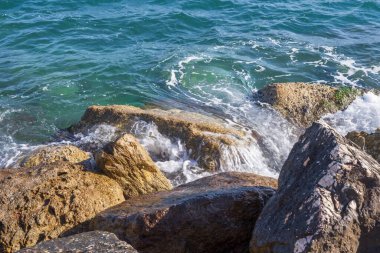 Atina gezinti güvertesinde gün batımının ışınlarında dalgalanan dalgalarla kayalık deniz kıyısı