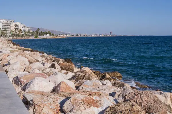 Dalgalar halinde akan turkuaz deniz suyuyla kayalık kıyılar ve kalın beyaz deniz köpüğü oluşturur..
