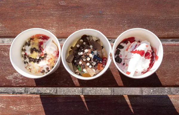 Dolapta donmuş Yunan yoğurdu ve güneş ışığı altında ahşap bankta malzemeler var.