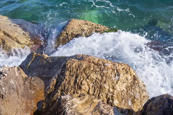 Atina gezinti güvertesinde gün batımının ışınlarında dalgalanan dalgalarla kayalık deniz kıyısı