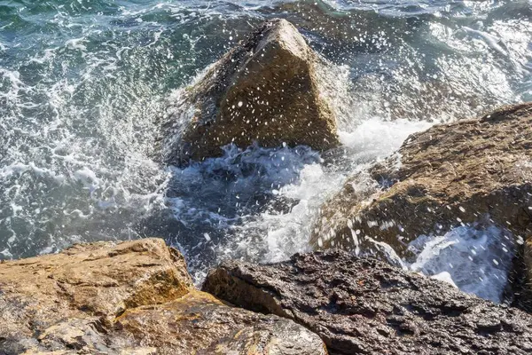 Atina gezinti güvertesinde gün batımının ışınlarında dalgalanan dalgalarla kayalık deniz kıyısı