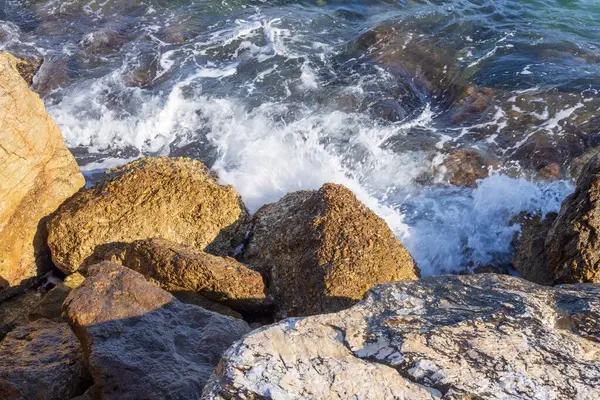 Atina gezinti güvertesinde gün batımının ışınlarında dalgalanan dalgalarla kayalık deniz kıyısı