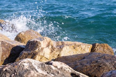 Atina gezinti güvertesinde gün batımının ışınlarında dalgalanan dalgalarla kayalık deniz kıyısı