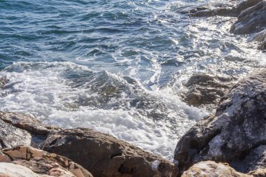 Atina gezinti güvertesinde gün batımının ışınlarında dalgalanan dalgalarla kayalık deniz kıyısı