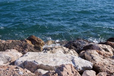 Atina gezinti güvertesinde gün batımının ışınlarında dalgalanan dalgalarla kayalık deniz kıyısı