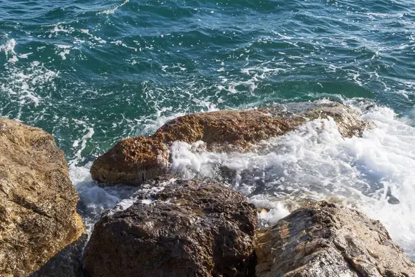 Atina gezinti güvertesinde gün batımının ışınlarında dalgalanan dalgalarla kayalık deniz kıyısı