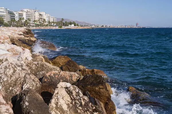 Atina gezinti güvertesinde gün batımının ışınlarında dalgalanan dalgalarla kayalık deniz kıyısı