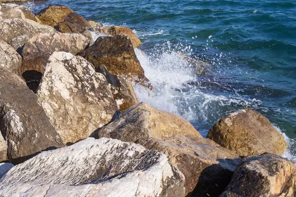 Atina gezinti güvertesinde gün batımının ışınlarında dalgalanan dalgalarla kayalık deniz kıyısı