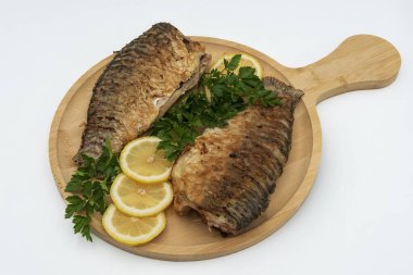 Tahta tahtada taze limon dilimleri ve maydanozlu garnitürle servis edilen kızarmış balık.