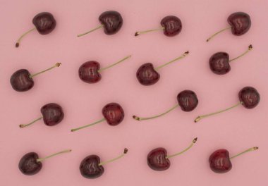 Kırmızı kirazlar pembe arka planda sıralanmış. Tasarım ve reklam için böğürtlen doğal arka plan