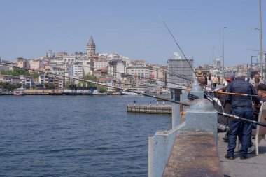 İstanbul, Trkiye 'deki Galata Köprüsü' nde camiler ve arka planda ufuk çizgisi olan bir grup balıkçı balık tutuyor. İstanbul, 20 Mayıs 2025