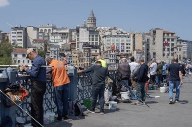 İstanbul, Trkiye 'deki Galata Köprüsü' nde camiler ve arka planda ufuk çizgisi olan bir grup balıkçı balık tutuyor. İstanbul, 20 Mayıs 2025