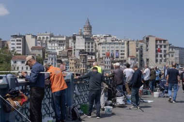 İstanbul, Trkiye 'deki Galata Köprüsü' nde camiler ve arka planda ufuk çizgisi olan bir grup balıkçı balık tutuyor. İstanbul, 20 Mayıs 2025