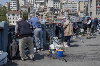 İstanbul, Trkiye 'deki Galata Köprüsü' nde camiler ve arka planda ufuk çizgisi olan bir grup balıkçı balık tutuyor. İstanbul, 20 Mayıs 2025