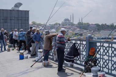 İstanbul, Trkiye 'deki Galata Köprüsü' nde camiler ve arka planda ufuk çizgisi olan bir grup balıkçı balık tutuyor. İstanbul, 20 Mayıs 2025