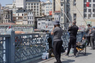 İstanbul, Trkiye 'deki Galata Köprüsü' nde camiler ve arka planda ufuk çizgisi olan bir grup balıkçı balık tutuyor. İstanbul, 20 Mayıs 2025