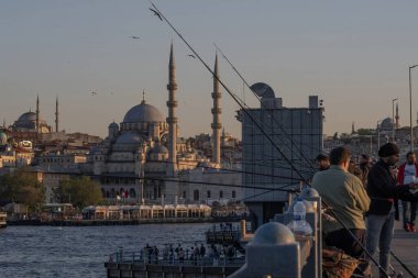 İstanbul, Trkiye 'deki Galata Köprüsü' nde camiler ve arka planda ufuk çizgisi olan bir grup balıkçı balık tutuyor. İstanbul, 20 Mayıs 2025