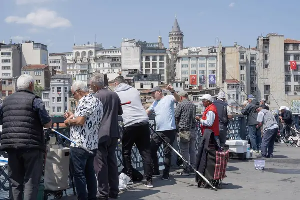 İstanbul, Trkiye 'deki Galata Köprüsü' nde camiler ve arka planda ufuk çizgisi olan bir grup balıkçı balık tutuyor. İstanbul, 20 Mayıs 2025