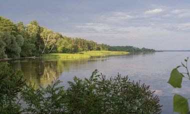 Yazın ormanlık ve bulutlu gökyüzü ile sakin nehir manzarası