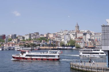 İstanbul 'un şehir kıyısı. Yolcu feribotları Golden Horn' dan geçiyor. Tarihi Galata Kulesi, yoğun binalar, sakin sular ve güneşli bir günde berrak gökyüzü ile şehir silueti..