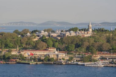 Topkapı Sarayı kompleksi. Etrafı orman parklarıyla çevrili. Boğaz 'ın diğer tarafından görülüyor. İstanbul 'daki ünlü tarihi mekan sıcak günbatımı tonlarıyla aydınlanıyor. İstanbul 20 Mayıs 2025